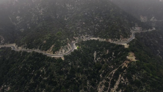 航拍的一个蜿蜒的道路在一个雾蒙蒙的森林在山(圣安妮塔峡谷，美国加州)视频素材