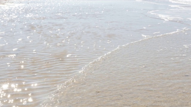 泡沫的海浪蔓延在阳光明媚的海滩夏日假期背景4K视频素材