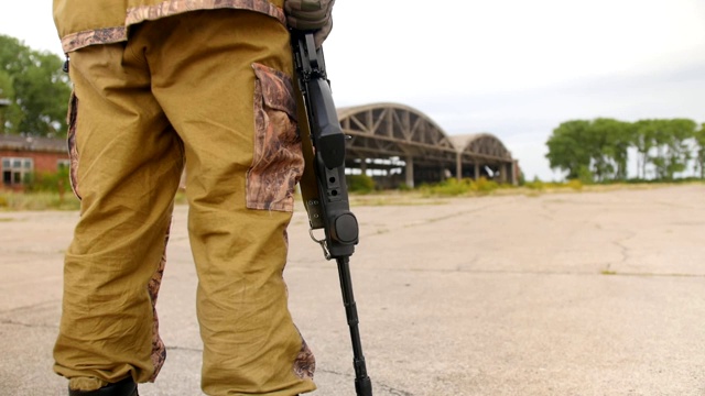 激光标签的游戏。airsoft的游戏。一名身穿制服的士兵拿着一把卡拉什尼科夫突击步枪站在那里。中景镜头。视频素材