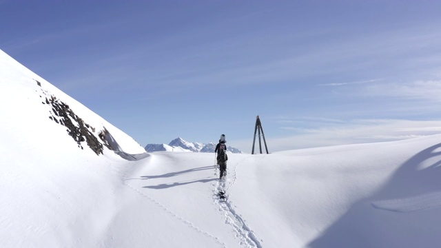 滑雪板在雪山鸟瞰图上行走在雪鞋攀登。人们带着滑雪板在冬季登山。滑雪旅游和冬季运动。冬天的活动视频素材