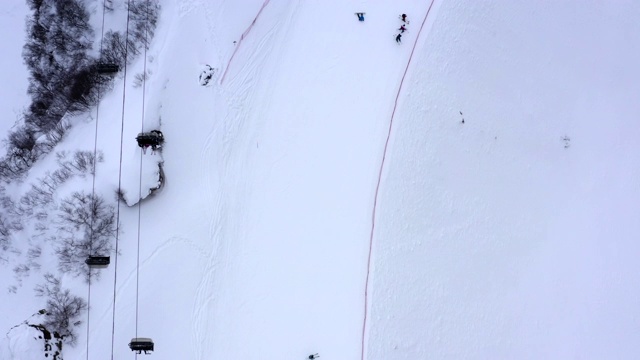 鸟瞰滑雪场雪山上滑雪、滑板的人们。无人机可以看到人们在山坡上滑雪和滑雪板。冬季活动及运动视频素材