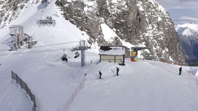 空中景观雪山山峰滑雪胜地。人们在滑雪场滑雪和滑板滑雪。无人机观看雪山冬季度假村。运动与活动概念视频素材