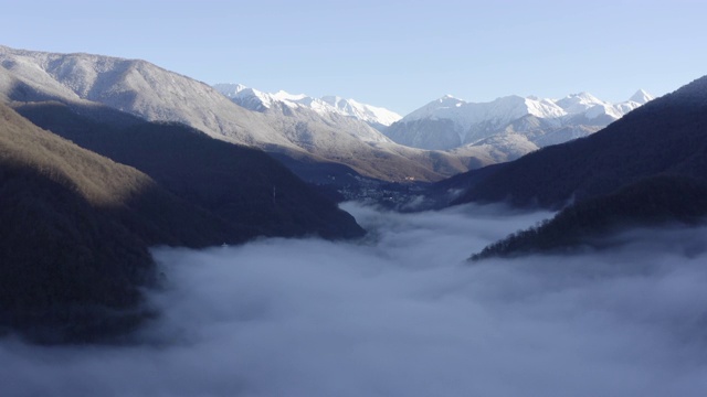 无人机在山谷的白色薄雾中飞行。空中景观雾云与雪峰山。空中无人机在高地和山脉上空的雾霾风景视频素材