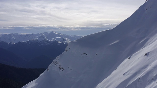 美丽的空中景观冬季山和雪坡在晴朗的天空背景。无人机飞越雪山山谷。有雪峰和明亮天空的山脉视频素材