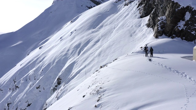 两名游客在雪山中滑雪，而冬季徒步旅行。冬天在雪山里徒步旅行和爬山。滑雪旅游。冬季登山视频素材