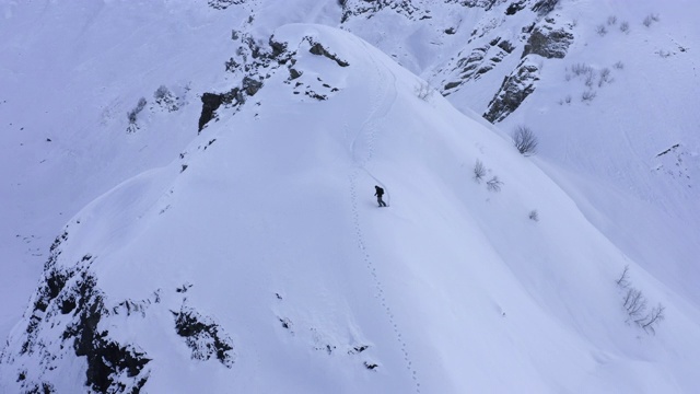 这个视频是关于从雪峰滑雪板在野生山无人机的观点。鸟瞰从雪山上滑雪的男人。极限运动和冬季活动视频素材