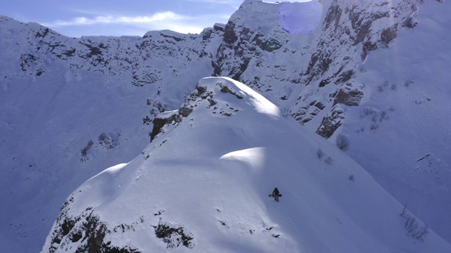 无人机从上面的雪山滑雪板与滑雪板行走。鸟瞰图滑雪板上升在雪山山顶。极限旅游和冬季运动。冬季活动与冒险视频素材