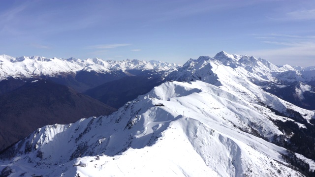 鸟瞰图高雪山在蓝天的背景。雪山山顶无人机观景滑雪缆车站及缆车通道。冬季的山脊和山坡视频素材