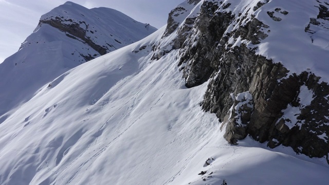 登山者在雪山滑雪和滑雪板，而冬季登山。滑雪旅游和雪山徒步旅行。无人机观看美丽的雪山山峰在冬季景观视频素材