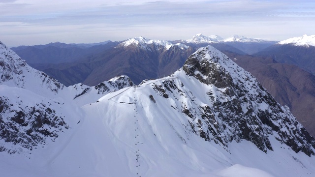 雪峰的山峰和滑雪电梯的交通在滑雪胜地无人机视图。雪山上滑雪者和滑板者的滑雪缆车。空中景观，雪峰和冬季山视频素材