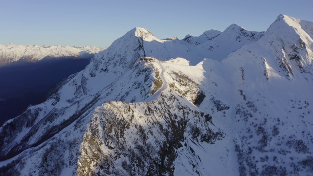 美丽的雪山景观在晴朗的天空背景从飞行的无人机。鸟瞰图冬季山和滑雪电梯在冬季度假村。山顶的高山斜坡及滑雪缆车视频素材