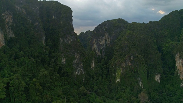 天线。惊人的电影风格的视频巨大的山脉和雨林在泰国南部。无人机飞越高峰。太阳在山后耀斑。两只鸟在四旋翼机附近飞行。视频素材