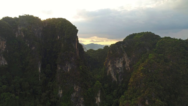 天线。惊人的电影风格的视频巨大的山脉和雨林在泰国南部。无人机飞越高峰。太阳在山后耀斑。两只鸟在四旋翼机附近飞行。视频素材