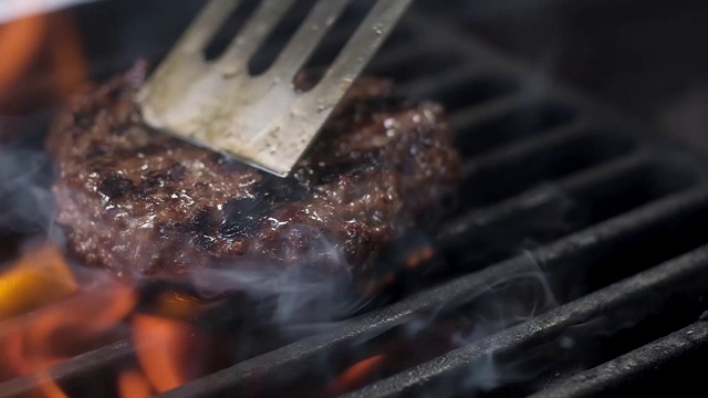 厨师在热烤架上为汉堡铲转动肉。视频素材