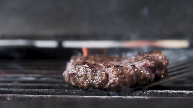 把做汉堡的肉放在烤架上烤慢镜头特写。视频素材