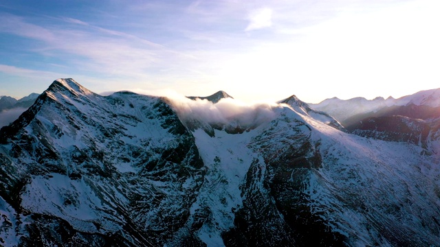 傍晚鸟瞰图积雪的阿尔卑斯山峰与夕阳的光束，霍赫陶恩国家公园，奥地利视频素材