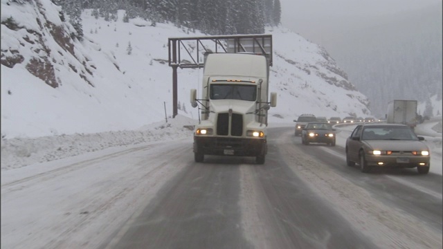 一辆半挂车在雪山公路上缓缓上坡。视频素材