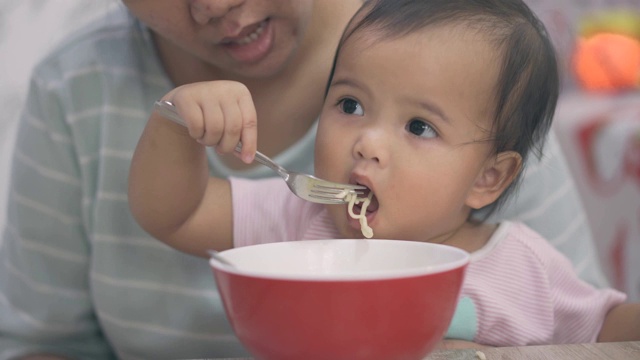 母亲给婴儿女儿喂面条视频素材