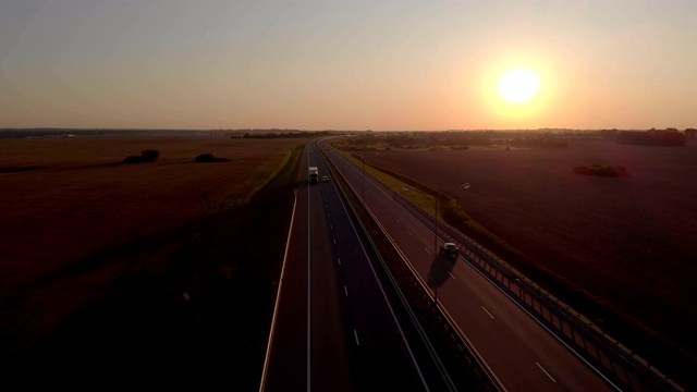 许多汽车是移动的夕阳。空中拍摄的车辆在美丽的乡村道路在日落。鸟瞰道路上的汽车与日落的背景。视频素材