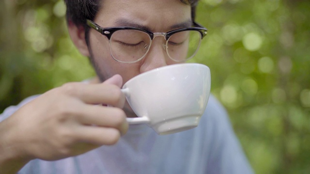 亚洲男人在花园里喝热拿铁咖啡视频素材