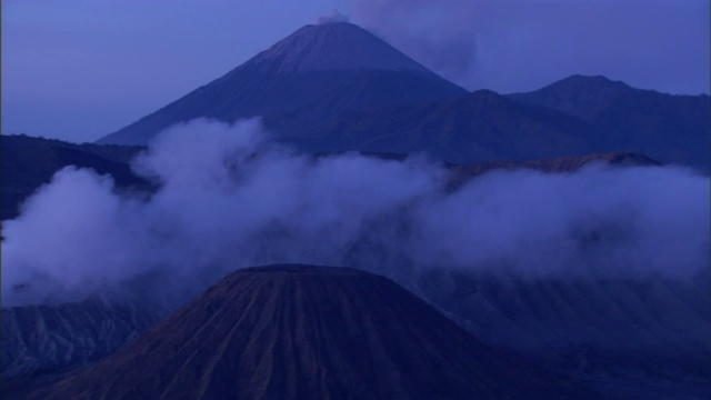 火山灰从两座火山升起，漂浮在第三座火山之上。视频素材