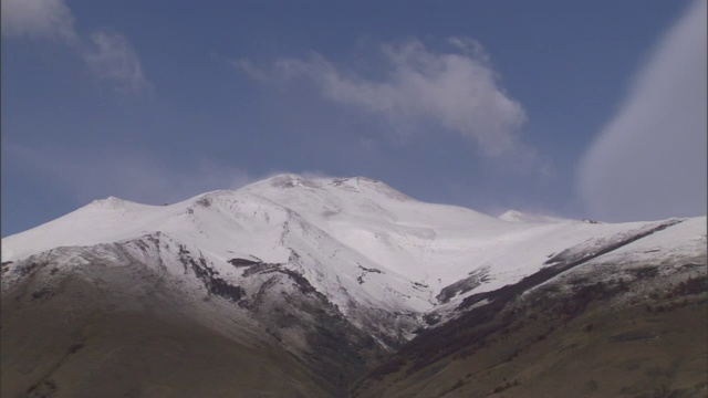 缕缕的云在白雪覆盖的山顶上移动。视频素材