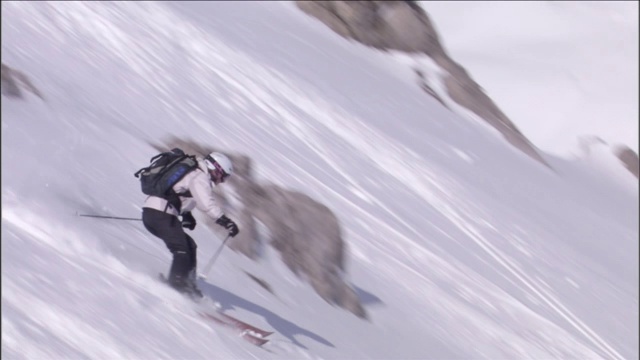 滑雪者在陡坡上滑过岩石。视频素材