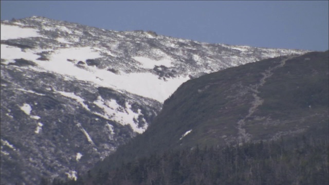 零零碎碎的雪依附在岩石嶙峋的山坡上。视频素材