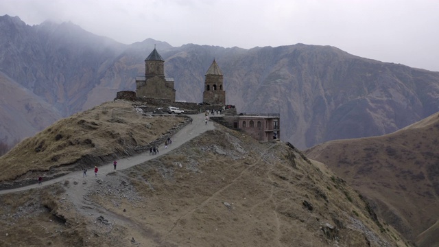 鸟瞰哈萨克山高地上的古格鲁吉亚教堂。古老的正统寺庙Gergeti格鲁吉亚，steantsminda在城市和山谷背景视频素材