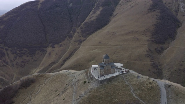 空中俯瞰卡兹贝克山高地上的古格鲁吉亚教堂。古老的正统寺庙Gergeti格鲁吉亚，steantsminda在城市和山谷背景视频素材