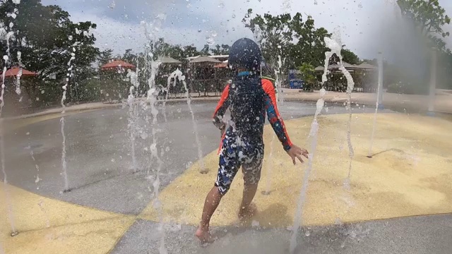 小男孩正在水上乐园的水隧道里奔跑。视频素材