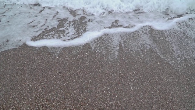 带着泡沫的海浪冲刷着卵石滩视频素材