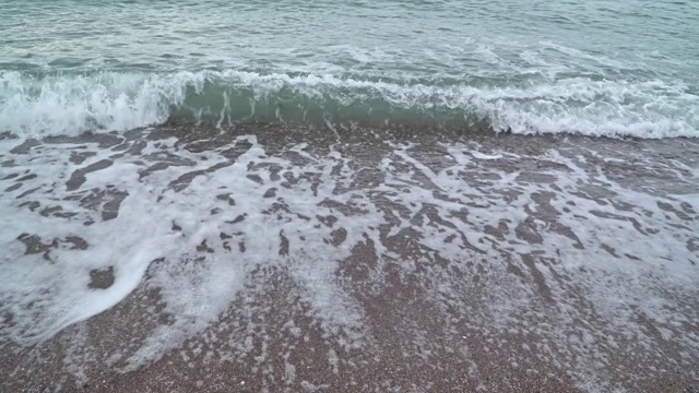 带着泡沫的海浪冲刷着卵石滩视频素材