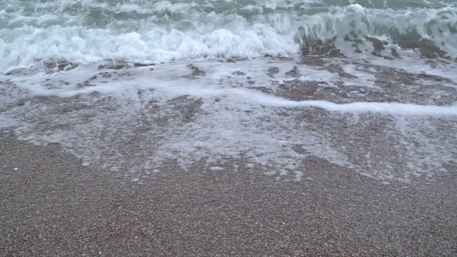 带着泡沫的海浪冲刷着卵石滩视频素材