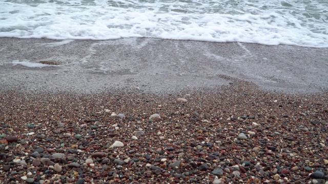 带着泡沫的海浪冲刷着卵石滩视频素材