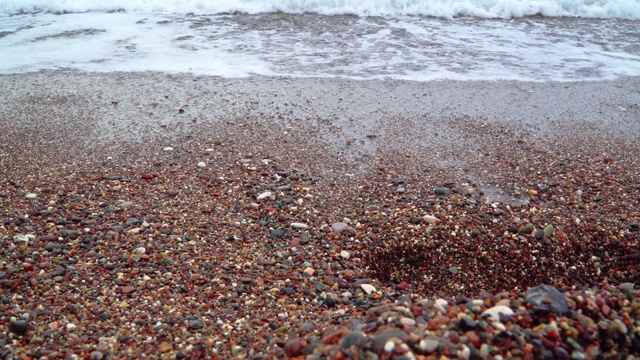 带着泡沫的海浪冲刷着卵石滩视频素材