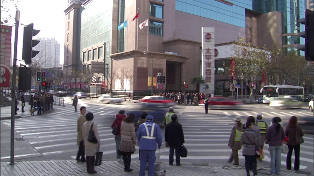 在繁忙的市中心十字路口，行人在使用人行横道前要等待警察阻止交通。视频素材