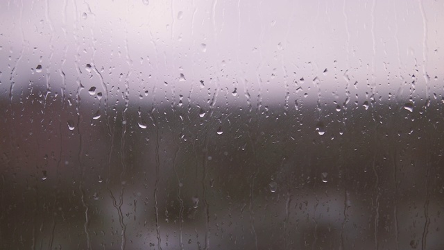 雨滴落在窗户上的电影效果。雨点打在玻璃上，背景模糊视频下载