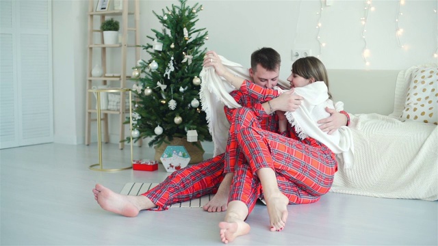 穿着红睡衣的情侣在圣诞树旁视频素材