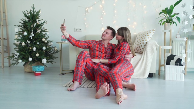 一对年轻夫妇在圣诞树旁自拍视频素材