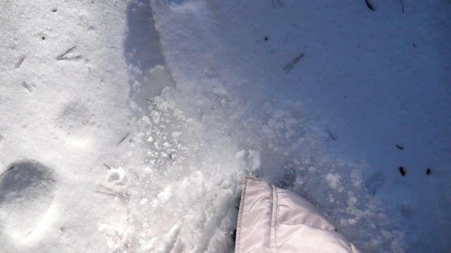 女人的腿踩在深雪和踢它的特写。在寒冷的冬日，徒步行走在白雪覆盖的森林里。女孩去户外。洁白的雪被阳光照亮。慢动作俯视图视频素材