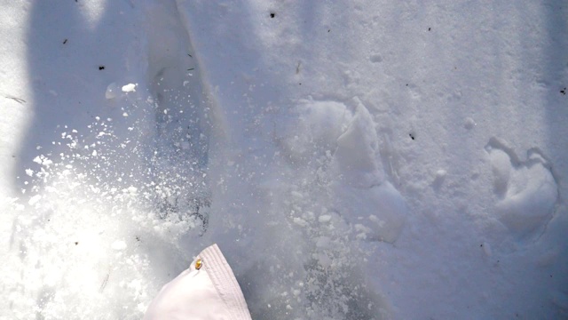 女人的腿踩在深雪和踢它的特写。在寒冷的冬日，徒步行走在白雪覆盖的森林里。女孩去户外。洁白的雪被阳光照亮。慢动作俯视图视频素材