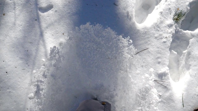 女人的腿踩在深雪和踢它的特写。在寒冷的冬日，徒步行走在白雪覆盖的森林里。女孩去户外。洁白的雪被阳光照亮。慢动作俯视图视频素材