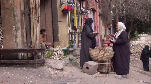 两个穿着传统服装的埃及妇女站在一个篮子周围交换钱。视频素材