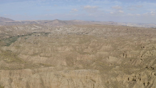 无人机在西班牙格拉纳达内华达山脉的蓝天中拍摄的Gorafe, Desierto de los colorado的干燥山谷和山脉。在安达卢西亚，有植被的西班牙沙漠峡谷。缓慢的移动非常广泛。视频素材