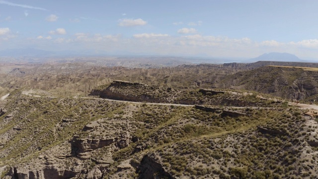 无人机在西班牙格拉纳达内华达山脉的蓝天中拍摄的Gorafe, Desierto de los colorado的干燥山谷和山脉。在安达卢西亚，有植被的西班牙沙漠峡谷。翻过4K山。视频素材