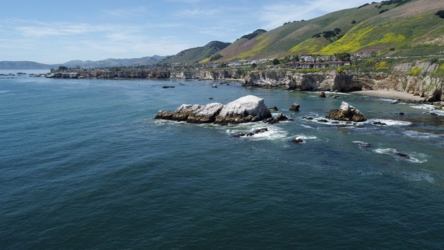 在阳光明媚的春日，加州西海岸太平洋上的小城市Pismo Beach附近的悬崖、岩石和偏远的101公路的海岸线全景鸟瞰。无人机4K超高清视频与静态摄像头。视频素材