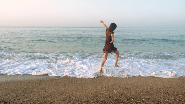 Costa del Maresme海岸。快乐的漂亮女人在卡莱拉海滩上玩耍，在沙滩上奔跑，在地中海的海浪中嬉戏。巴塞罗那。西班牙4 k。视频素材