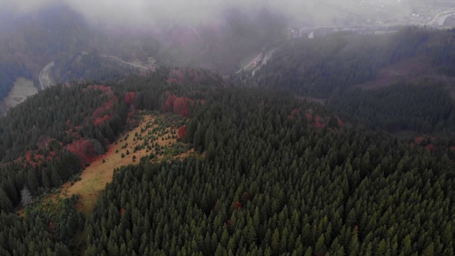 透过喀尔巴阡山脉的迷雾，从无人机看到一片空地、秋天的森林、河流和村庄。视频素材