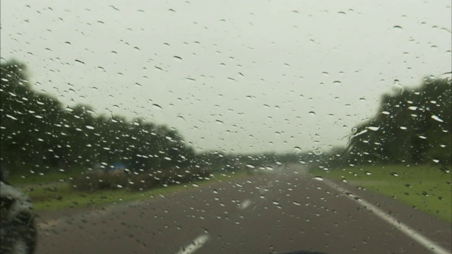 一辆汽车在雨中沿着双车道的高速公路行驶。视频素材